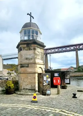 a lighthouse with a cross on top of it at Three Bridges Waterfront in North Queensferry