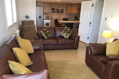 a living room with brown leather couches and a kitchen at Beautiful 3-Bed Apartment in Gourock in Gourock