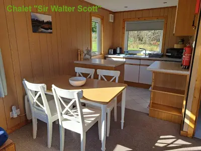 a kitchen with a wooden table and chairs in a kitchen at Airdeny Chalets in Taynuilt