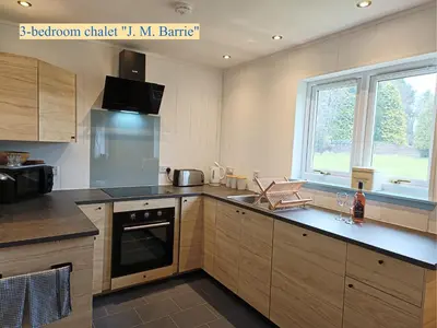 a kitchen with wooden cabinets and a large window at Airdeny Chalets in Taynuilt
