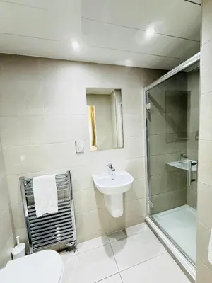 a white bathroom with a sink and a shower at Sandyford Lodge in Glasgow