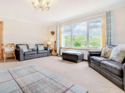 a living room with two couches and a large window at 3 Bedroom luxury home, hot tub, stunning views of Killin, sitting on the River Dochart in Killin
