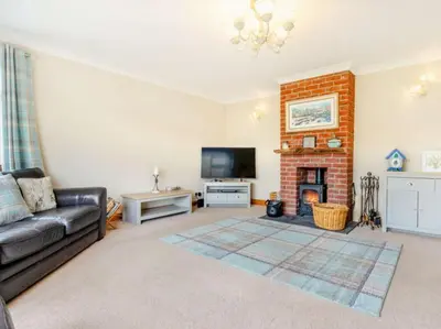 a living room with a couch and a fireplace at 3 Bedroom luxury home, hot tub, stunning views of Killin, sitting on the River Dochart in Killin