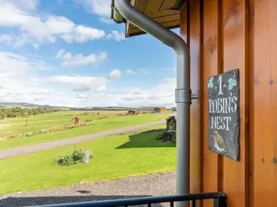 a sign on the side of a building with a view of a field at Chalet Loch Leven Lodge 16 Robin's Nest by Interhome in Kinross