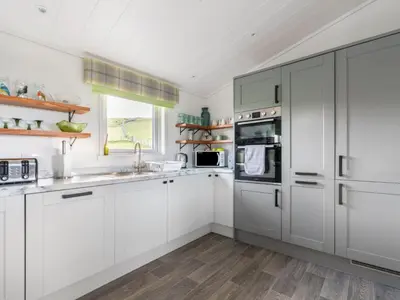 a white kitchen with white cabinets and a window at Chalet Loch Leven Lodge 16 Robin's Nest by Interhome in Kinross