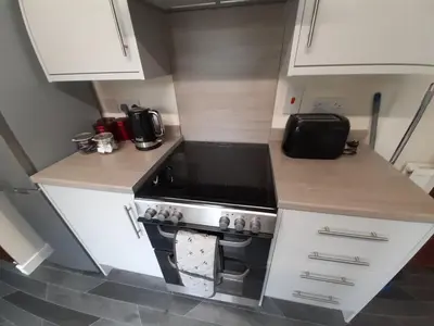 a small kitchen with a stove and white cabinets at Carvetii - Zelda House - 4 bedroom house, sleeps 8 in Oakley