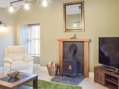 a living room with a wood stove and a television at Dairy Cottage - Uk39522 in Maybole
