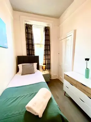 a bedroom with a large bed and a window at Historic 2-Bed Paisley Retreat, Airport & Station in Paisley