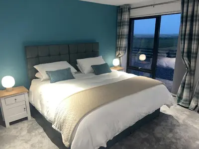 a bedroom with a large bed and a large window at Machrie View in Port Ellen