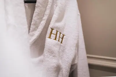 a white towel with a gold logo on it at Huntly House - A Residence Like No Other in Glasgow