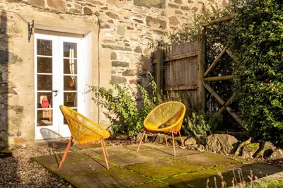 two yellow chairs sitting in front of a building at Charming Cardoon Cottage in beautiful village in Comrie