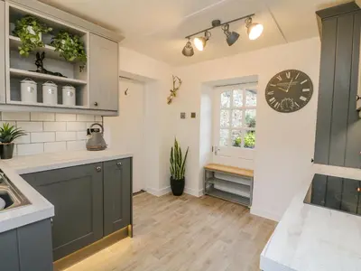 a kitchen with green cabinets and a clock on the wall at Inglis Nook Cottage in Lochearnhead