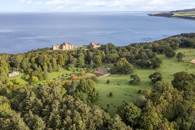 an aerial view of a castle on a hill next to the water at Clocktower - Culzean Castle in Maybole