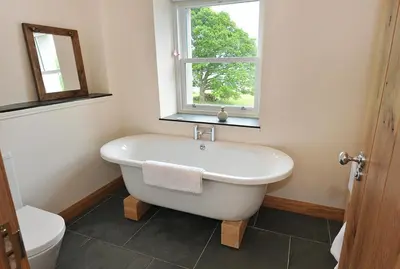 a bathroom with a white tub and a window at Achaglachgach Stables in Tarbert