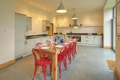 a large kitchen with a long wooden table and red chairs at Achaglachgach Stables in Tarbert
