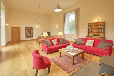 a living room with two red couches and a table at Achaglachgach Stables in Tarbert