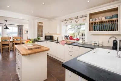 a kitchen with white cabinets and a counter top at Ardlarach Lodge in Cullipool