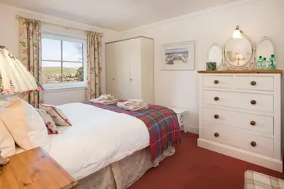 a bedroom with a bed and a dresser and a window at Ardlarach Lodge in Cullipool