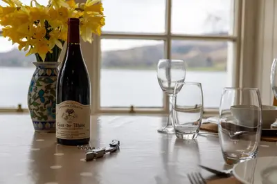 a bottle of wine sitting on a table with glasses at Rhunacairn in Oban