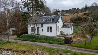 an old white house on the side of a hill at Rhunacairn in Oban