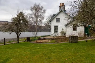 a white house on the shore of a lake at Rhunacairn in Oban