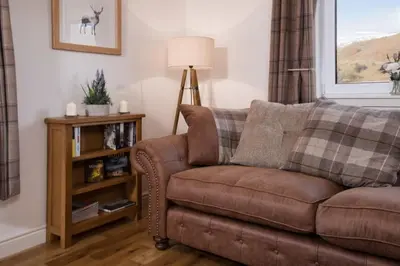 a living room with a brown couch and a lamp at Ardchyle House in Killin
