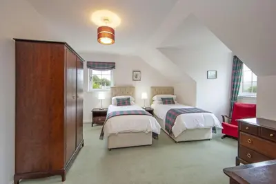 a attic bedroom with two beds and a dresser at Branter Lodge in Strachur