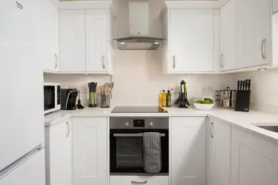 a kitchen with white cabinets and a stove top oven at Gaidrew Cottage in Drymen