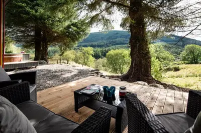 a patio with a table and chairs and a tree at Am Bothan in Lochearnhead