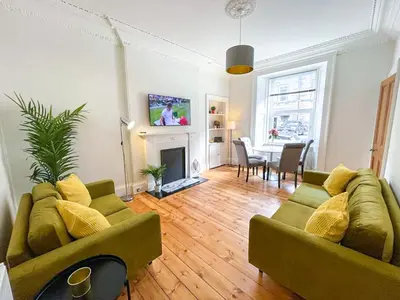 a living room with two green couches and a table at Desirable 2 Bed Apt Near Edinburgh Castle in Edinburgh