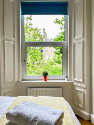 a bedroom with a window with a blanket on a bed at Desirable 2 Bed Apt Near Edinburgh Castle in Edinburgh