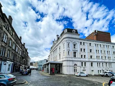 a large white building on a city street with cars at Desirable 2 Bed Apt Near Edinburgh Castle in Edinburgh