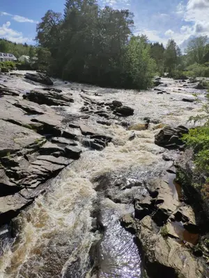 a river with rocks and trees in the background at CRAIGLEA HEATHER in Killin