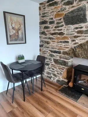 a table and chairs in a room with a stone wall at CRAIGLEA HEATHER in Killin
