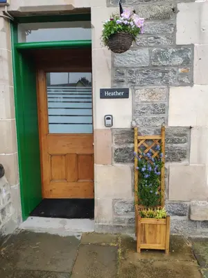 a door to a building with a basket of flowers at CRAIGLEA HEATHER in Killin