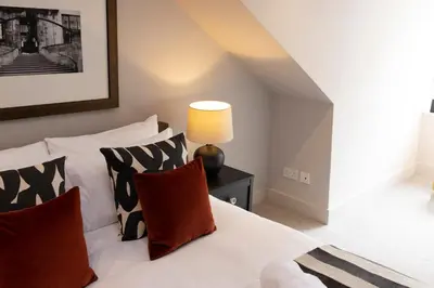 a bedroom with a white bed with pillows and a lamp at JOIVY Luxury Flat near Edinburgh Castle in Edinburgh