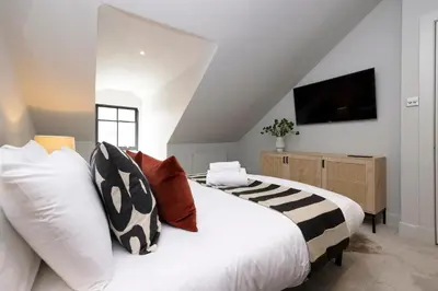 a bedroom with a white bed with pillows and a television at JOIVY Luxury Flat near Edinburgh Castle in Edinburgh