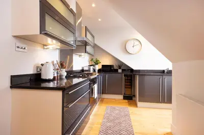 a kitchen with stainless steel appliances and a clock on the wall at JOIVY Luxury Flat near Edinburgh Castle in Edinburgh