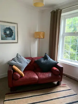 a red couch sitting in a living room with pillows at Cedarbank’s - 'Little Art House' in Kirn