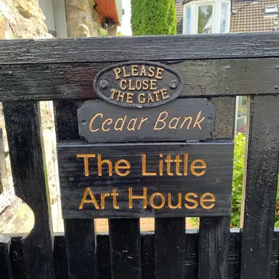 a sign for the cafe cedar bank on a bench at Cedarbank’s - 'Little Art House' in Kirn