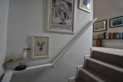a stairway with a bird sitting on a shelf next to a staircase at Yewtree Cottage - 'The Art House' and Garden in Hunters Quay