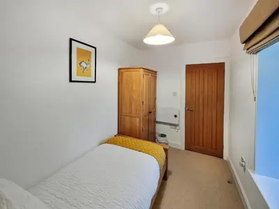 a small bedroom with a bed and a wooden cabinet at Boatman's Cottage At Invernian Mor in Inverinan Beg