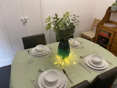 a table with plates and a vase with flowers on it at Arden House in Comrie