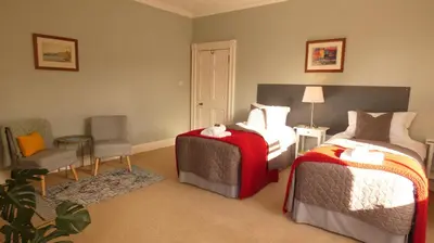 a hotel room with two beds and a chair at Kirkland House B&B in Tarbert