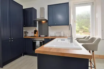 a kitchen with blue cabinets and a sink and a window at Findhorn Upper Apartment in Kames