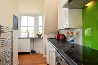 a kitchen with green and white cabinets and a counter top at Arran View in Lochgilphead