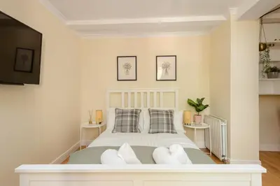 a bedroom with a bed with white furniture and a flat screen tv at Dean Village Hideaway by Calton Living in Edinburgh