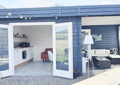 a blue house with a patio with a living room at Romantic Rural Lodge - Private Outdoor Kitchen & Cosy Covered Lounge - Perth and Kinross - Hot Tub not included in Crook of Devon