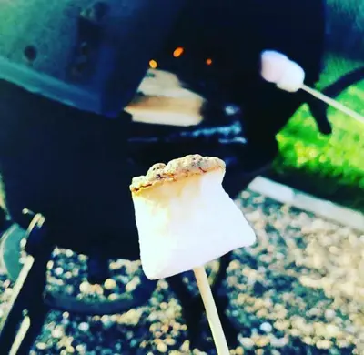 a piece of food on a stick in front of a grill at Romantic Rural Lodge - Private Outdoor Kitchen & Cosy Covered Lounge - Perth and Kinross - Hot Tub not included in Crook of Devon