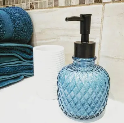a blue glass bottle sitting on a bathroom counter at Rural Private Lodge - With Hot Tub - Outdoor Kitchen and Covered Lounge for Two in Crook of Devon